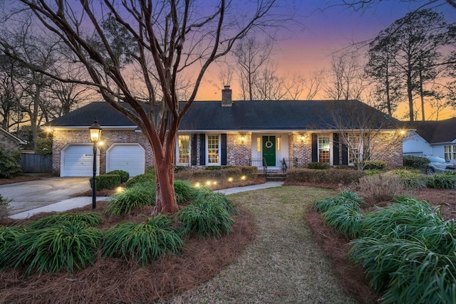 ranch-style home with a garage, brick siding, a chimney, and driveway