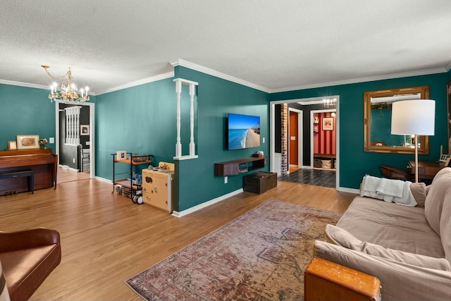 living area with a chandelier, a textured ceiling, baseboards, and wood finished floors