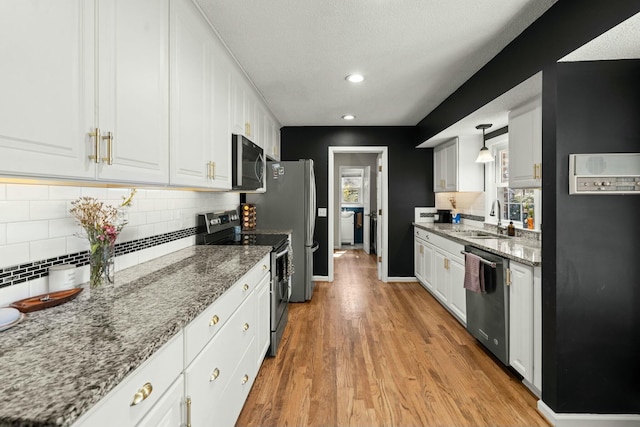 kitchen with a sink, appliances with stainless steel finishes, white cabinets, and light wood finished floors