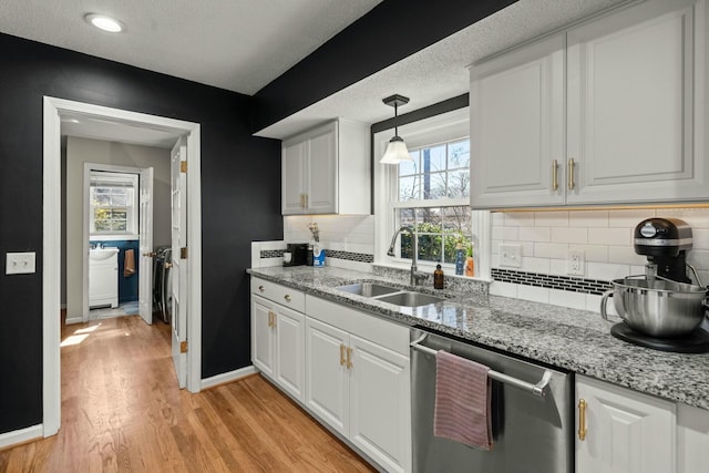 kitchen with baseboards, a sink, white cabinets, light wood-style floors, and dishwasher