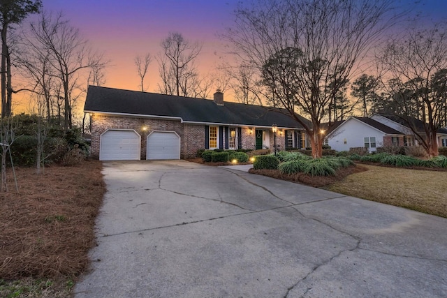 single story home with brick siding, a chimney, concrete driveway, and an attached garage