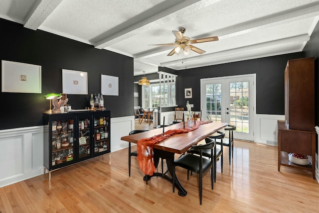 dining space with beamed ceiling, a healthy amount of sunlight, french doors, and light wood-type flooring