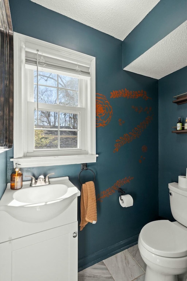 bathroom with a textured ceiling, toilet, vanity, and baseboards