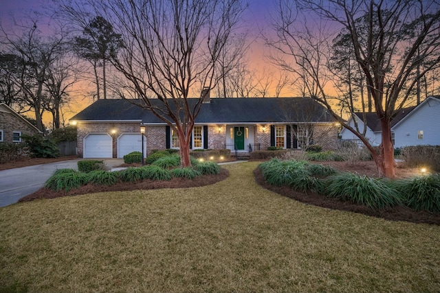 view of front of property with brick siding, driveway, an attached garage, and a front yard