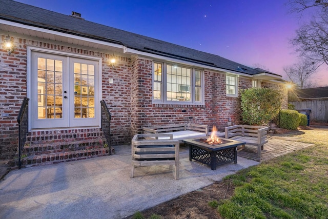 patio terrace at dusk featuring french doors, fence, and a fire pit