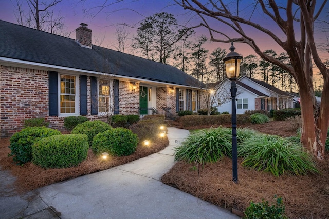 single story home featuring brick siding and a chimney