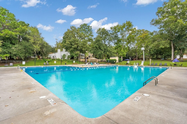 community pool with a patio area, a yard, and fence