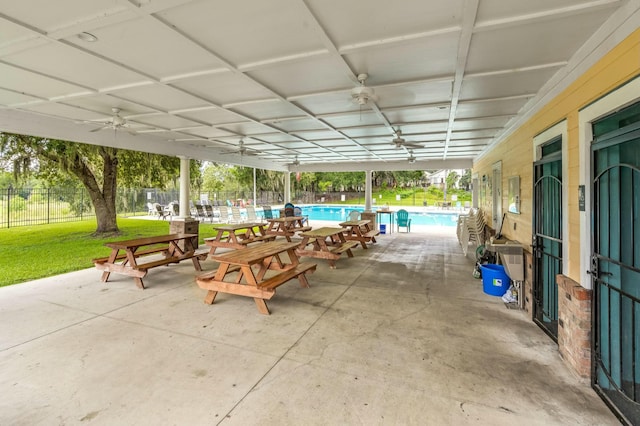 view of patio featuring a community pool, a ceiling fan, and fence