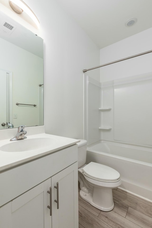 bathroom featuring visible vents, toilet, wood finished floors, vanity, and  shower combination