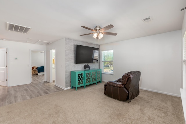 living area with visible vents, baseboards, carpet, and ceiling fan