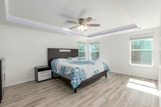 bedroom with visible vents, a raised ceiling, multiple windows, and light wood finished floors