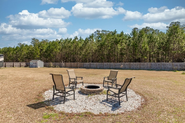 view of yard featuring a storage unit, a fire pit, a fenced backyard, and an outdoor structure