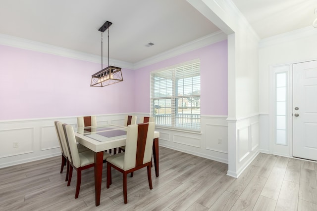 dining room with light wood finished floors, wainscoting, and ornamental molding