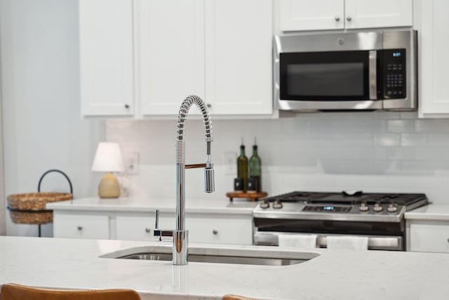 kitchen featuring backsplash, stainless steel appliances, white cabinetry, and sink