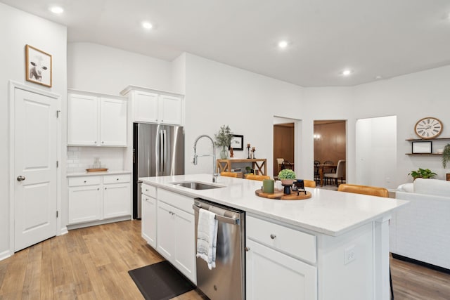 kitchen with appliances with stainless steel finishes, a center island with sink, white cabinetry, and sink