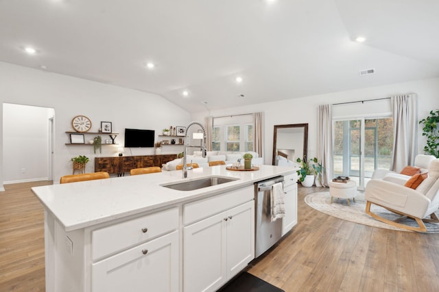 kitchen with white cabinets, vaulted ceiling, sink, a center island with sink, and dishwasher