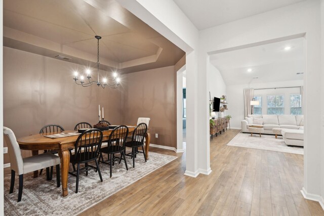 dining room featuring a raised ceiling, hardwood / wood-style floors, and a chandelier