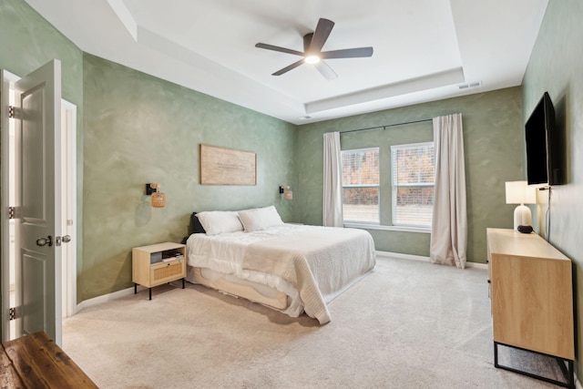 carpeted bedroom featuring ceiling fan and a tray ceiling