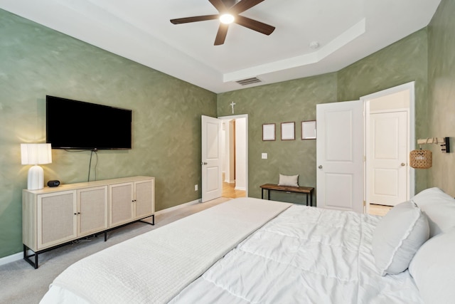 bedroom with a tray ceiling, ceiling fan, and light colored carpet