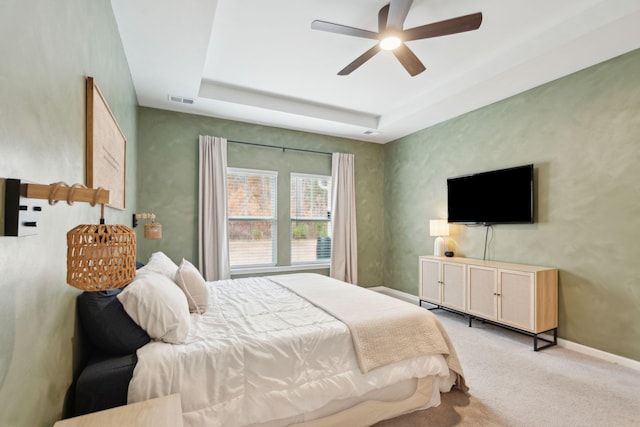 bedroom featuring ceiling fan, a raised ceiling, and light colored carpet