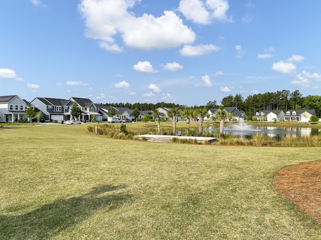 view of property's community with a lawn and a water view