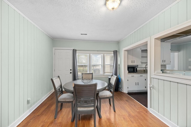 dining space featuring crown molding, hardwood / wood-style floors, and wooden walls