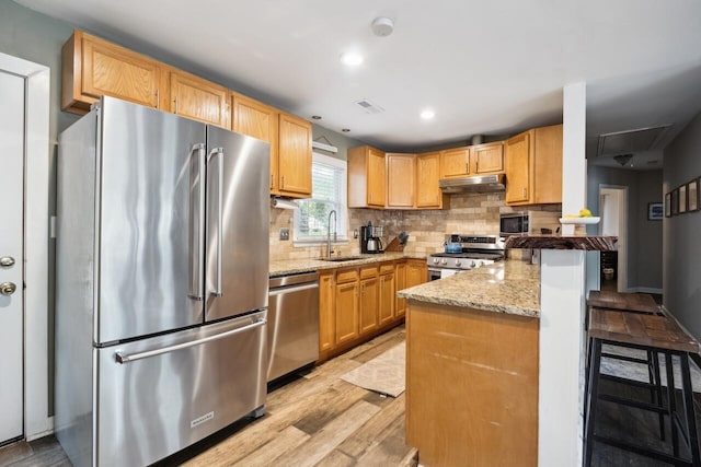 2158 Till Rd, Charleston, SC 29414 - kitchen with appliances with stainless steel finishes, under cabinet range hood, a peninsula, light stone countertops, and light wood-style flooring