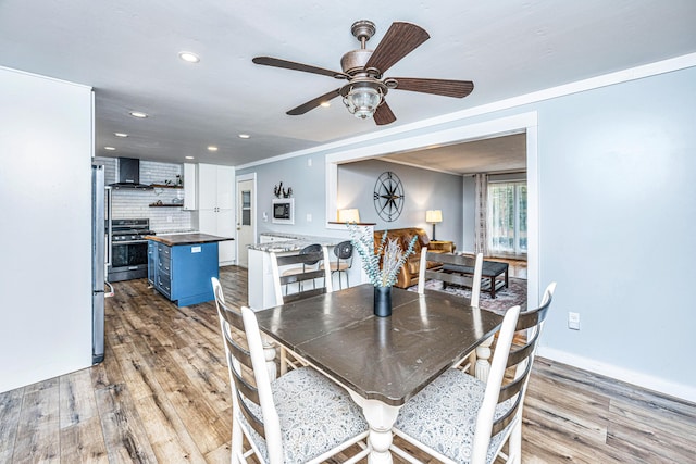 dining area featuring ceiling fan, light wood-type flooring, and ornamental molding