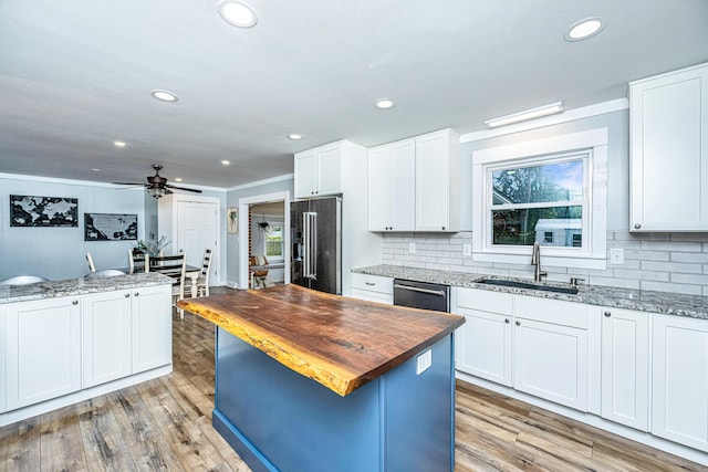 kitchen with light stone counters, stainless steel appliances, white cabinetry, and sink