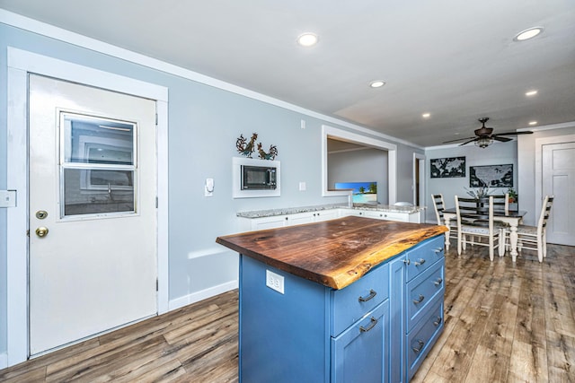 kitchen featuring wood counters, ceiling fan, blue cabinetry, wood-type flooring, and a center island