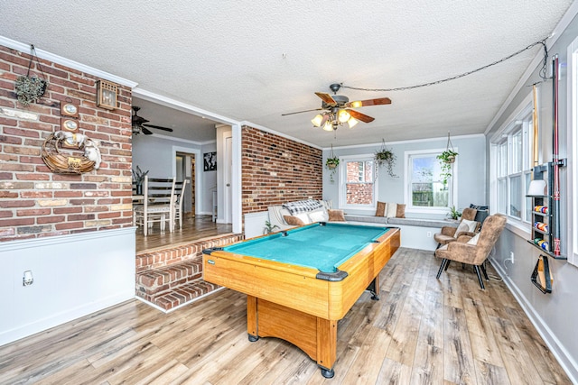 rec room featuring brick wall, a textured ceiling, ornamental molding, and pool table