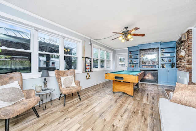 game room with a textured ceiling, light hardwood / wood-style floors, ornamental molding, and pool table