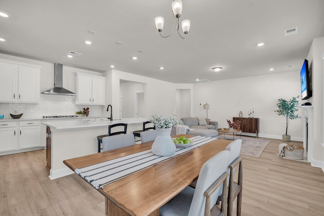 dining space featuring sink, a chandelier, and light hardwood / wood-style floors