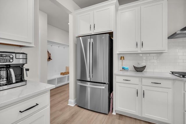 kitchen with decorative backsplash, stainless steel appliances, light hardwood / wood-style floors, and white cabinets