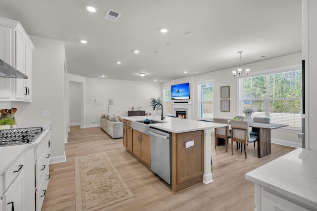 kitchen with sink, white cabinetry, decorative light fixtures, a center island with sink, and stainless steel appliances