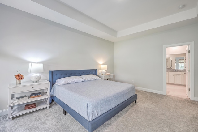 bedroom featuring ensuite bath, carpet floors, and a tray ceiling