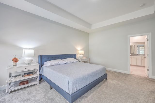 carpeted bedroom featuring a tray ceiling and connected bathroom