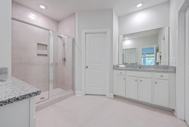 bathroom with an enclosed shower, vanity, and tile patterned flooring