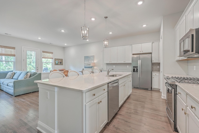 kitchen with a center island with sink, appliances with stainless steel finishes, backsplash, white cabinets, and sink