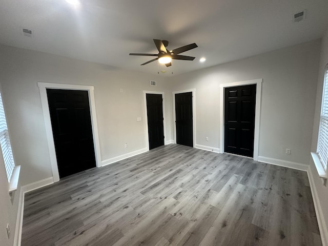 unfurnished bedroom with connected bathroom, ceiling fan, light hardwood / wood-style floors, and a walk in closet