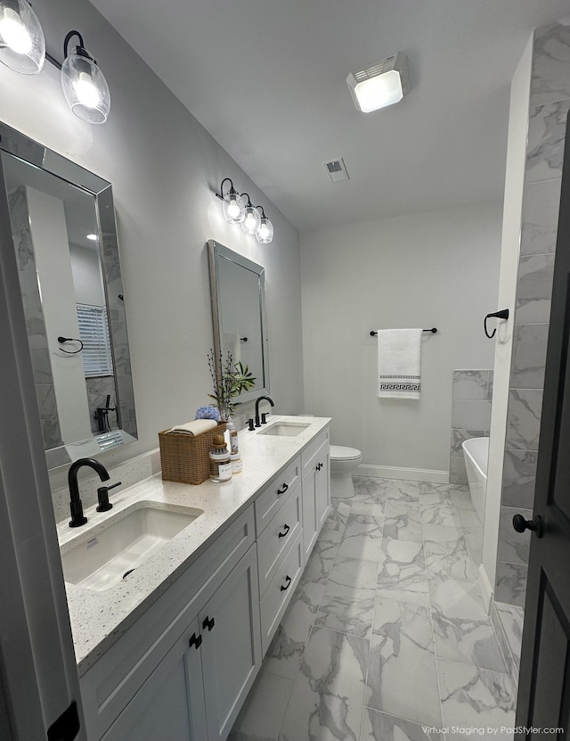 bathroom with vanity, toilet, and a tub to relax in