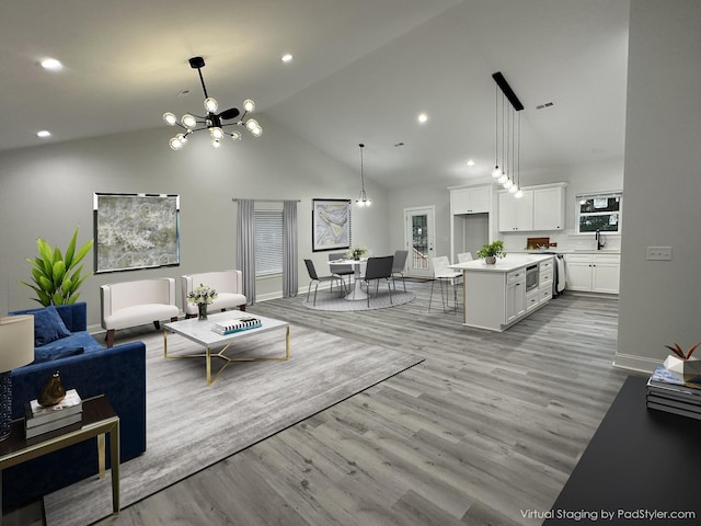 living room featuring light hardwood / wood-style floors, sink, high vaulted ceiling, and a chandelier