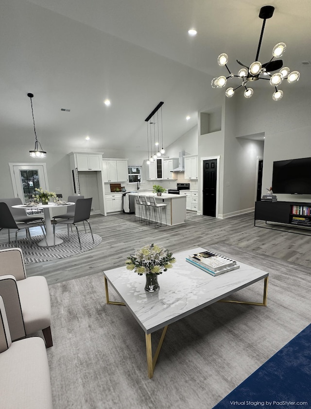 living room featuring light wood-type flooring, high vaulted ceiling, and an inviting chandelier