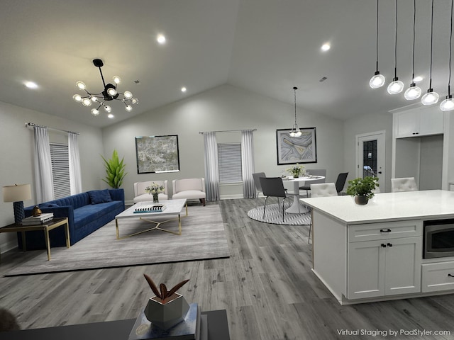 living room featuring lofted ceiling, light hardwood / wood-style floors, and a notable chandelier