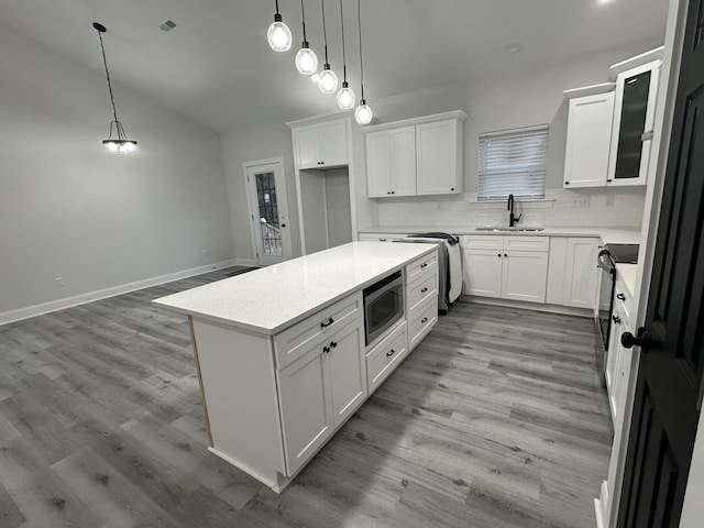 kitchen with built in microwave, sink, white cabinets, and pendant lighting