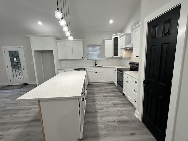 kitchen featuring white cabinetry, sink, hanging light fixtures, black / electric stove, and a kitchen island