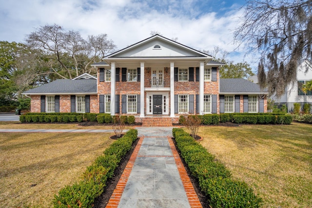 greek revival house featuring a front lawn, covered porch, brick siding, and a shingled roof