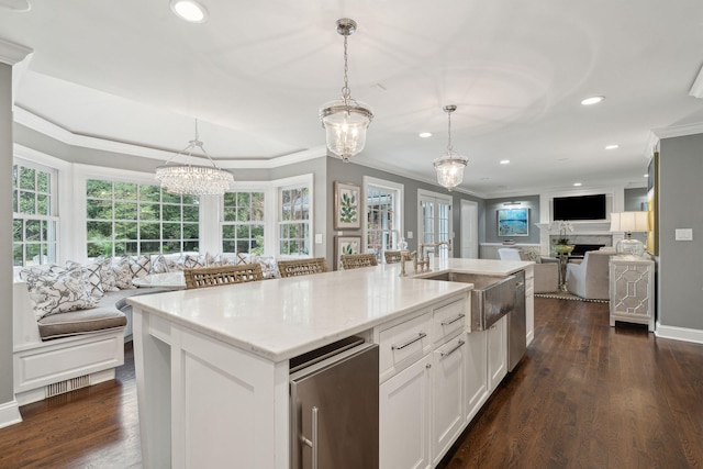 kitchen with a sink, open floor plan, dark wood-style flooring, and crown molding