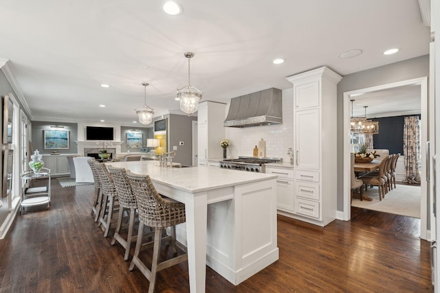 kitchen with a sink, open floor plan, a fireplace, wall chimney range hood, and range