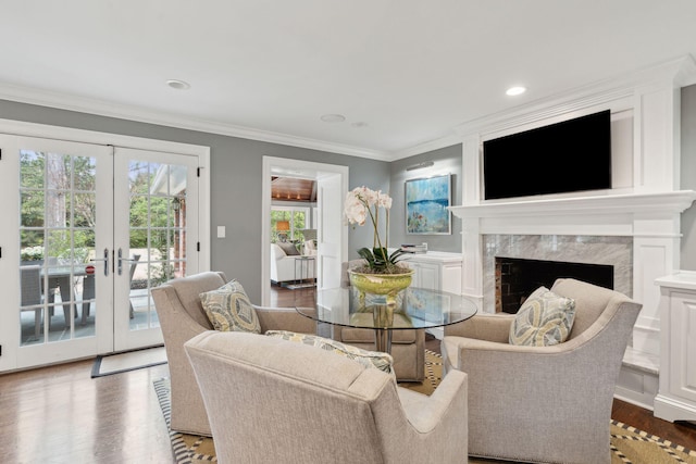 living area with ornamental molding, wood finished floors, a high end fireplace, recessed lighting, and french doors